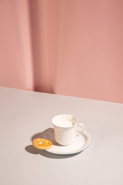 Fresh milk with sweet cookie on table against pink backdrop