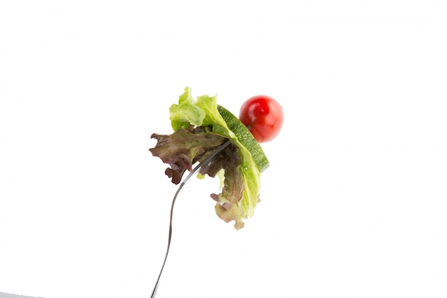 Fresh mixed vegetables on a fork isolated on white background.