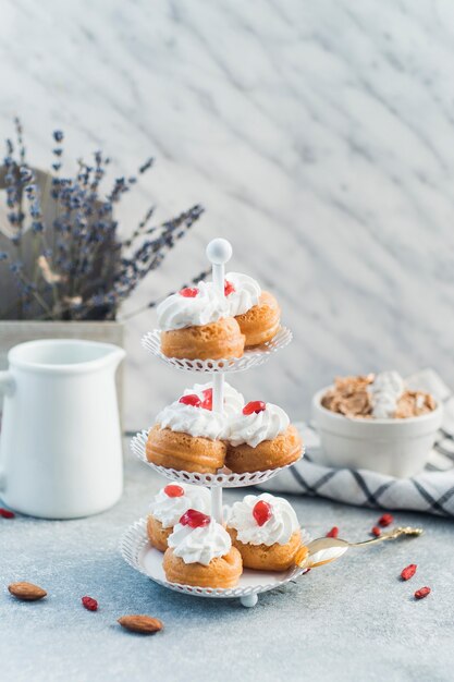 Fresh muffins arranged on cake stand near nut food over concrete surface