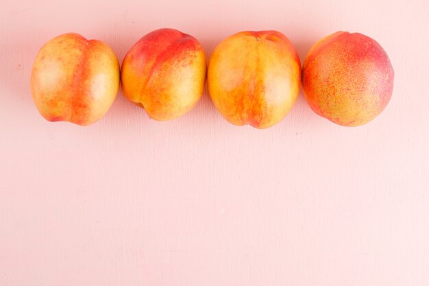 Fresh nectarines on a pink surface. flat lay.