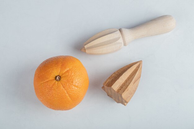 Fresh orange fruit with wooden reamers isolated on a white background.