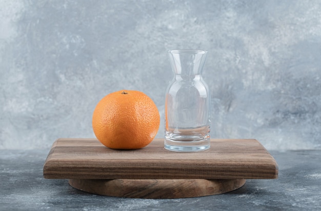 Fresh orange and glass on wooden board.