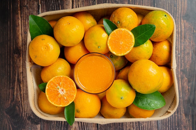 Fresh orange juice in the glass on dark wooden background