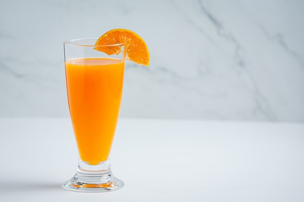 Fresh orange juice in the glass on marble background