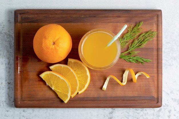 Fresh orange juice with sliced or whole fruits on wooden board.