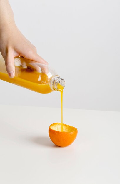 Fresh orange smoothie being poured in an orange peel