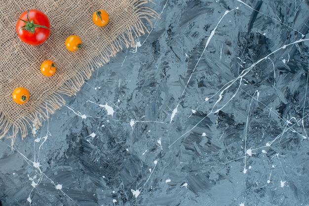 Foto gratuita pomodori arancioni freschi e pomodori rossi su un tovagliolo di tela, sullo sfondo di marmo.