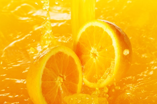 Fresh oranges falling in juice