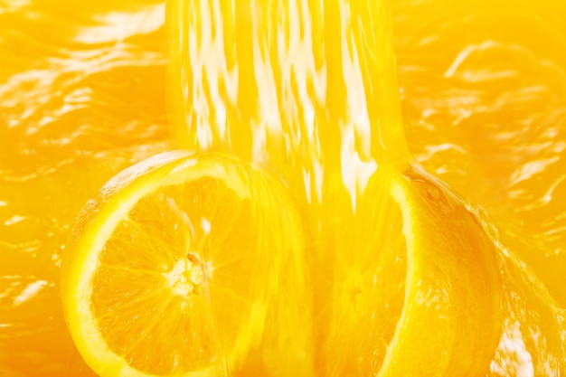 Свежие апельсины падают в сок