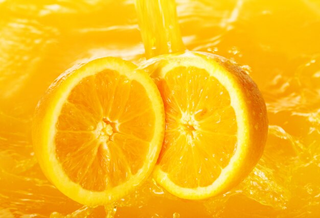 Fresh oranges falling in juice