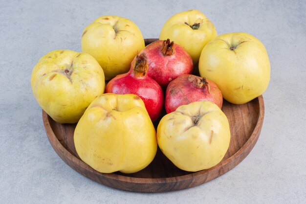 Fresh and organic apple quince and pomegranate on wooden board.