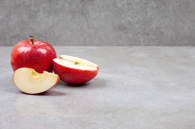 Fresh organic apples. Whole or sliced red apples on grey table.