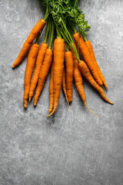 Fresh organic bunch of carrots on a gray kitchen top aerial view