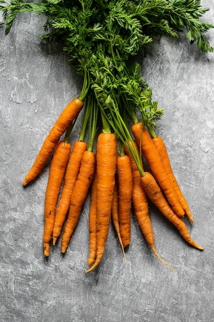 Fresh organic bunch of carrots on a gray kitchen top aerial view