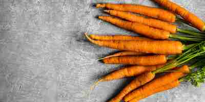 Free photo fresh organic bunch of carrots on a gray kitchen top aerial view