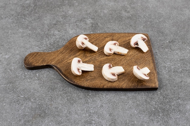 Fresh organic champignons slices on wooden cutting board.