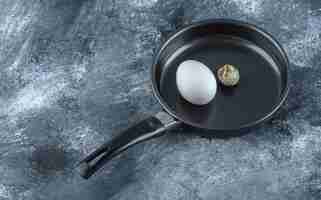 Free photo fresh organic chicken and quail eggs in black frying pan.