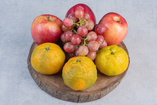 Свежие органические фрукты. Яблоко, виноград и мандарины на деревянной доске.
