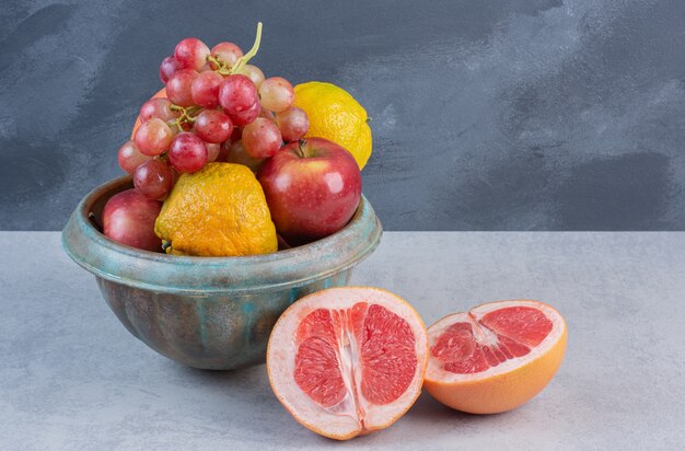 Fresh organic fruits in bowl on grey background. 