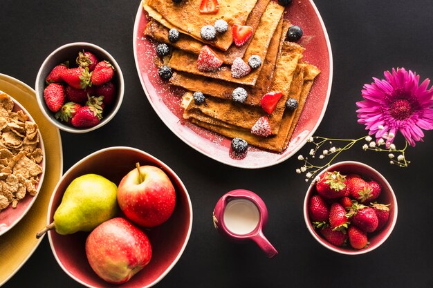 Fresh organic fruits with crepe breakfast on black background