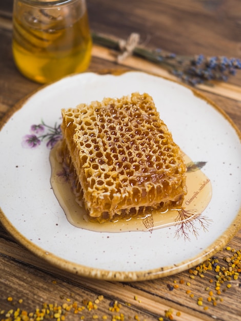 Foto gratuita favo organico fresco sul piatto con pollini d'api sopra la tavola