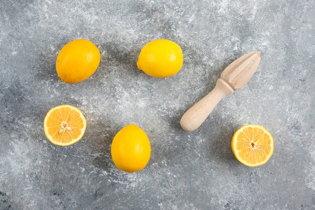 Fresh organic lemons and squeezer on grey surface.