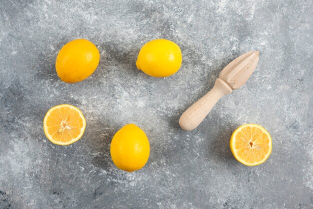 灰色の表面に新鮮な有機レモンと絞り器。