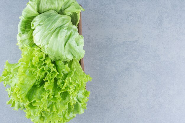 Fresh organic lettuce leaves in bowl on grey background. 