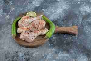 Foto gratuita cosce di pollo crudo biologico fresco e peperoni verdi sul tagliere di legno.