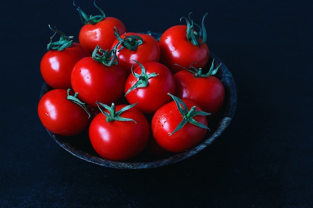 Fresh organic red tomatoes in black plate, close up, healthy concept, top view