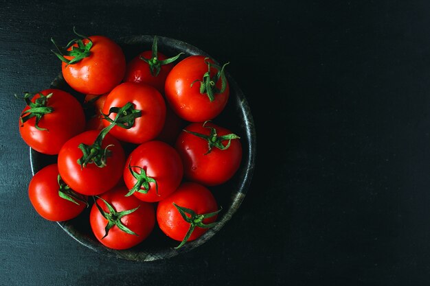 Fresh organic red tomatoes in black plate, close up, healthy concept, top view