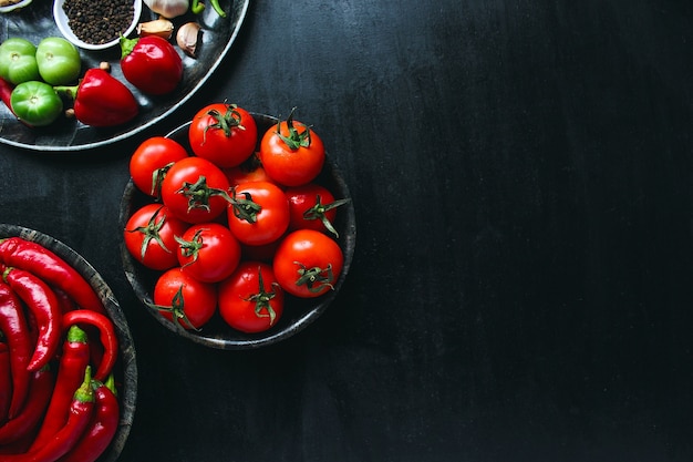 Fresh organic red tomatoes in black plate, close up, healthy concept, top view