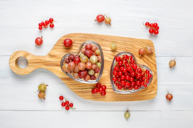 Fresh organic sweet gooseberries and red currant in bowls