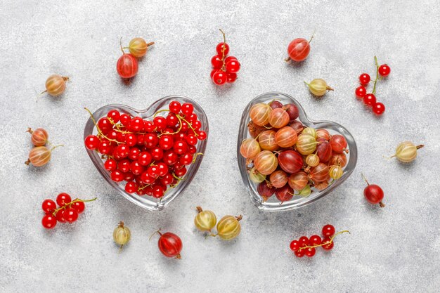 Fresh organic sweet gooseberries and red currant in bowls