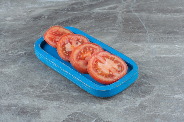 Free photo fresh organic tomato slices on blue wooden board