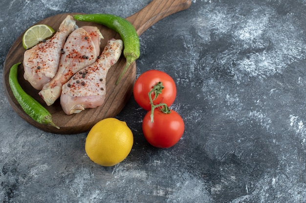 Fresh organic tomatoes, pepper and lemon with raw chicken legs.