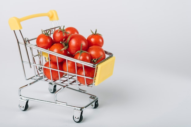 Fresh organic tomatoes in trolley on white backdrop