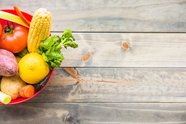 Fresh organic vegetables in bowl on wooden surface