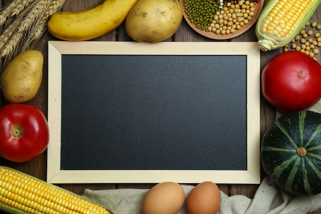 Fresh organic vegetables,fruits,eggs,beans,and corns with blackboard on vintage wooden table