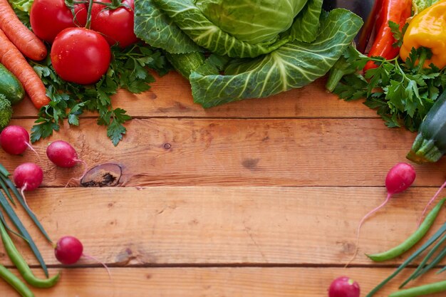 Fresh organic vegetables on a wooden boards background, top view. Healthy food concept.