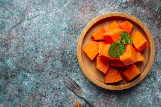 Fresh papaya, cut into pieces, put on a wooden plate.