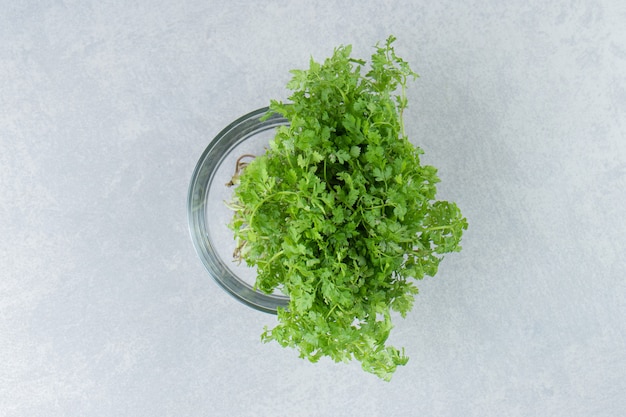 Free photo a fresh parsley in the glass , on the marble background.