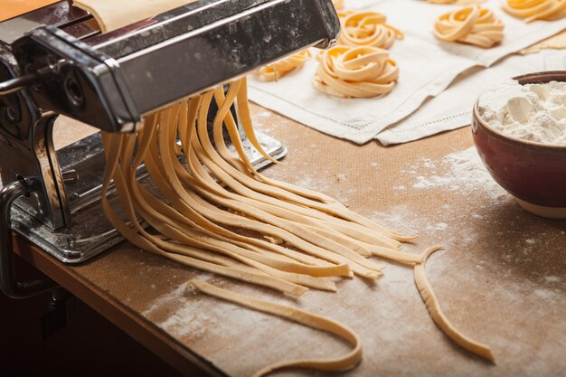 The fresh pasta and  machine on kitchen table