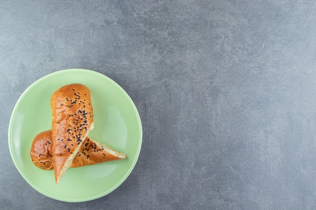 Fresh pastries with sesame seeds on green plate. 