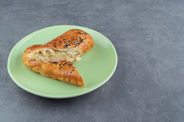 Fresh pastries with sesame seeds on green plate. 