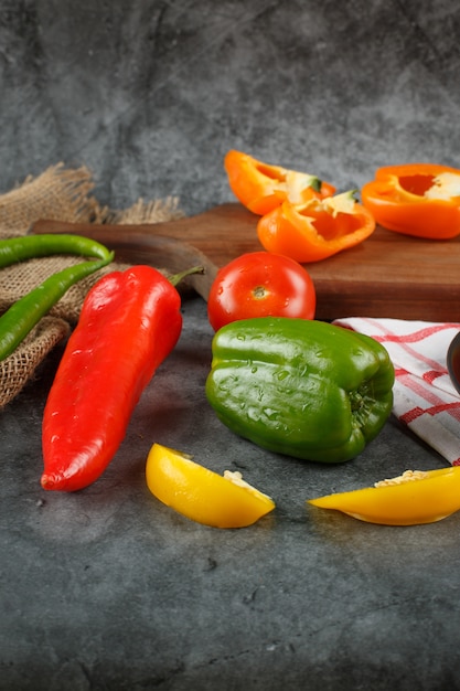 Fresh peppers on a stone background on a wooden board.