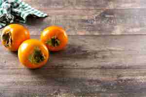 Free photo fresh persimmon fruit on wooden table