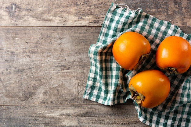 Free photo fresh persimmon fruit on wooden table