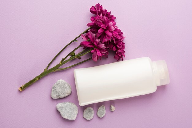 Fresh pink flowers; spa stones and closed bottle on pink background