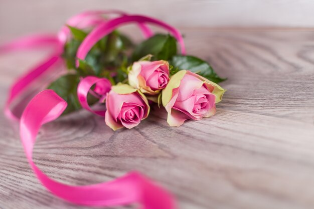 Fresh pink roses on wood